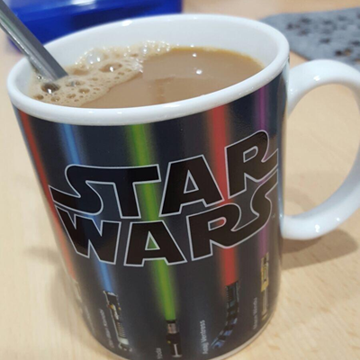 Star Wars mug with coffee and a spoon on a wooden surface